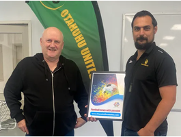 Friends of Football chair Josh Easby presents Otahuhu United chair Stephen West with the club’s framed poster.